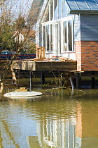 House protected by raised stilts alongside River Thames in February 2014 flood. Surrey, England, UK, 16th February 2014.
