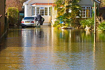Resident with car outside flooded home during February 2014 floods. Surrey, England, UK, 16th February 2014.