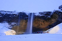 Tourists looking at Seljalandsfoss waterfall, Iceland, November 2012.