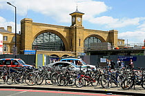 Bicycles attached to bike racks in front of taxis and traffic with King&#39;s Cross Station behind, London, England, UK, July 2013.