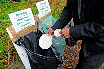 Man recycling cardboard mug and plate into the appropriate bag, Transition Waltham Forest event, Walthamstow, London, England, UK, October 2013.