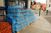 Packs of mineral drinking water in plastic bottles on a pallet for sale outside shop in Holloway, London Borough of Islington, England, UK, March 2013.