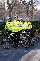 Metropolitan police officers wearing yellow reflective jackets on bicycles, Climate Change March, London England UK, December 2008.