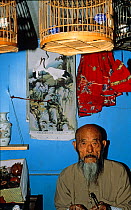 Bird trader with Siberian Rubythroat (Luscinia calliope) in Beijing bird market, China, 1993.