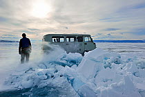 Van driving past pile of broken ice on Lake Baikal, Siberia, Russia, March.