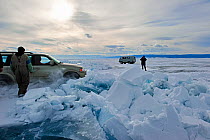 Car driving past piles of broken ice on Lake Baikal, Siberia, Russia, March.