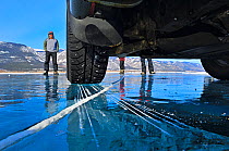 View of people standing on ice from underneath car, on the ice of Lake Baikal, Siberia, Russia, March. Property released and Model released.
