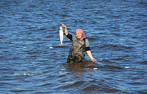 Zhenya Stoyanova, a Chukchi woman, holds up a Chum salmon she has caught in Anadyr Bay, Anadyr, Chukotka, Siberia, Russia. July 2013.