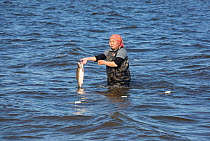 Zhenya Stoyanova, a Chukchi woman, removes a Chum salmon from her fishing net in Anadyr Bay, Anadyr, Chukotka, Siberia, Russia. July 2013.