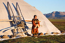 Nadia Takui, a Chukchi girl, dressed in a traditional reindeer skin Kerker (knee length coverall) outside a Yaranga (tent) at a reindeer herders' summer camp. Iultinsky District, Chukotka, Siberia, Ru...