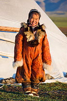 Nadia Takui, a Chukchi girl, dressed in a traditional reindeer skin Kerker (knee length coverall) outside a Yaranga (tent) at a reindeer herders' summer camp. Iultinsky District, Chukotka, Siberia, Ru...