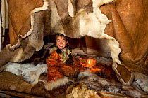 Nadia Takui, a Chukchi girl, dressed in a traditional reindeer skin Kerker, (knee length coverall) sitting at the edge of the polog (sleeping area) in a Yaranga (tent) at a reindeer herders' summer ca...
