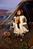 Nadia Takui, a Chukchi girl, dressed in a new Kerker (reindeer skin coverall) stands by a ritual fire at the entrance of a Yaranga (tent) at the start of the Chukchi 'Festival of the Young Reindeer' a...