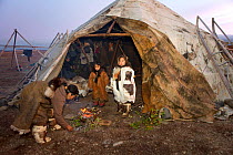 Yarosalva and Nadia, two Chukchi girls, stand by the entrance of a Yaranga (tent) while Tamara, Nadia's mother, tends a ritual fire at the start of the Chukchi 'Festival of the Young Reindeer' at a he...