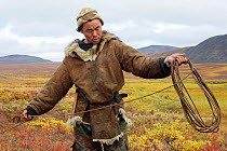 Sasha Takui, a Chukchi reindeer herder, coils up his lasso, while out working with his reindeer at their autumn pastures. Iultinsky District, Chukotka, Siberia, Russia, August 2013.