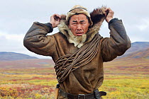 Sasha Takui, a Chukchi reindeer herder, pulls up the hood of his Kukhlyanka (reindeer skin parka) while out working with his reindeer at their autumn pastures. Iultinsky District, Chukotka, Siberia, R...
