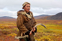 Sasha Takui, a hukchi reindeer herder, working with his reindeer at their autumn pastures. He is holding a curved throwing stick (Kenunen) which he uses to change the direction his reindeer are going....