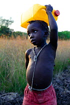 Child carrying water bottle over head, Eticoga Village, Orango Island, Guinea-Bissau, December 2013.