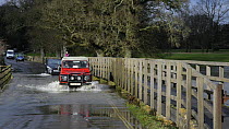Landrover and cars driving through floods caused by the River Avon bursting its banks, Lacock, Wiltshire, England, UK, February 2014.