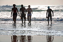 Four swimmers walking up beach, North Beach, Durban, KwaZulu-Natal, South Africa, August 2009.