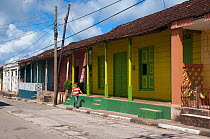 Man walking along row of colourful houses with wooden shutters, Baracoa, Guantanamo province, Eastern Cuba, November 2011.