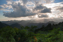 Forest covered mountains with sun shining through clouds, Baracoa Mountains, East Cuba, November 2011.