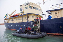 Tourists getting out of zodiac in to MS Origo, Svalbard, Norway, August 2011.