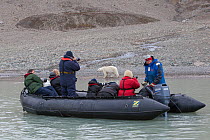 Tourists photographing a Polar bear (Ursos maritimus) from zodiac boat, Svalbard, Norway, August 2011.