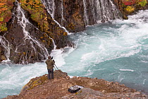 Photographer overlooking waterfall and river, Hraunfossar waterfalls, Hvita River, Iceland, September 2013.