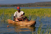 Fisherman in traditional boat removing fish from net, Lake Baringo, Kenya, October 2013.