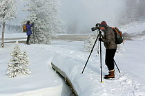Two photographers on path, Upper Geyser Basin, Yellowstone National Park, Wyoming, USA, February 2014.