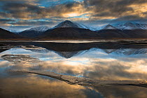 Mountains with tops covered in a light layer of snow reflected in water, Adventdalen, Spitsbergen, Svalbard, Norway, September 2013.