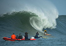 Surfer competing in the Mavericks 2014 surfing competition, watched by people on RIB, Half Moon Bay, California, USA, January 2014.