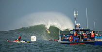 Harbour patrol boat and surfers competing in Mavericks Surfing Competition 2014, Half Moon Bay, California, USA, January.