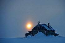 Old house covered in snow with setting sun, Wrangel Island, Far Eastern Russia, March 2011.