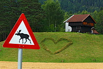 Heart shape in grass near farm, with Reindeer crossing sign, Telemark, Norway, August 2012.