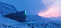 Svalbard Global Seed Vault at twilight, with glittering facade designed by artist Dyveke Sanne. Light reflected in steel, mirrors, and prisms in landscape, Svalbard, Norway, October 2012.
