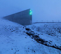 Svalbard Global Seed Vault in mist, with glittering facade designed by artist Dyveke Sanne. Light reflected in steel, mirrors, and prisms in landscape, Svalbard, Norway, October 2012.