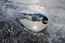 View to wintry landscape through hole in ice, Hornsund, Svalbard, Norway, September.