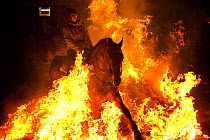 Young woman jumping through fire to purify her horse, during the Luminarias festival, held every January in San Bartolome de Pinares, Avila Province, Castile and Leon, Spain, January 2014.