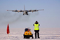 Lockheed C-130 Hercules transport plane equipped with skis coming in to land at Patriot Hills, with Antarctic Logistics and Expeditions staff watching, Antarctica.