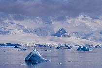 Small iceberg off Cuverville Island with Anvers Island as a backdrop, Antarctic Peninsula, Antarctica.