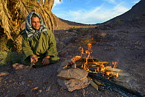 Local Berber man cooking Spiny-tailed lizard (Uromastyx nigriventris) on fire, near Ouarzazate, Morocco, October 2013.