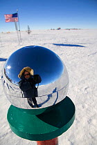 Self portrait of photographer Cherry Alexander in the reflection of the metallic sphere at the ceremonial South Pole, Antarctica.