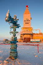 A 'Christmas tree' (valve assembly) in front of a gas drilling derrick in the South Tambey Gas Field, Yamal Peninsula, Siberia, Russia. February 2014.