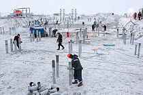 Workers wearing protective winter clothing against the cold at a construction site near Sabetta in the South Tambey Gas Field, Yamal Peninsula, Siberia, Russia. February 2014.