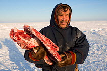 Grisha Vanuito, a Nenets herder, carrying reindeer meat at his winter camp in the South Tambey Gas Field, Yamal Peninsula, Siberia, Russia. February 2014.