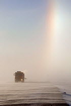 A sun dog (parhelion / parhelia) in the sky above a truck on a stormy winter's day near Sabetta in the South Tambey Gas Field, Yamal Peninsula, Siberia, Russia. February 2014.