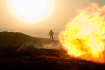 A gas field worker walking near a flare at a drilling site in the South Tambey Gas Field, Yamal Peninsula, Siberia, Russia. February 2014.