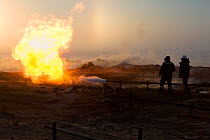 Two gas field workers standing near a flare at a drilling site in the South Tambey Gas Field, Yamal Peninsula, Siberia, Russia. February 2014.